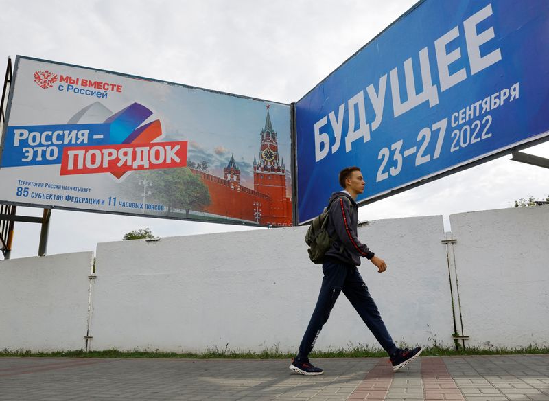 Un homme marche devant des panneaux au sujet d'un référendum sur le rattachement à la Russie des régions ukrainiennes contrôlées par la Russie, à Melitopol, en Ukraine