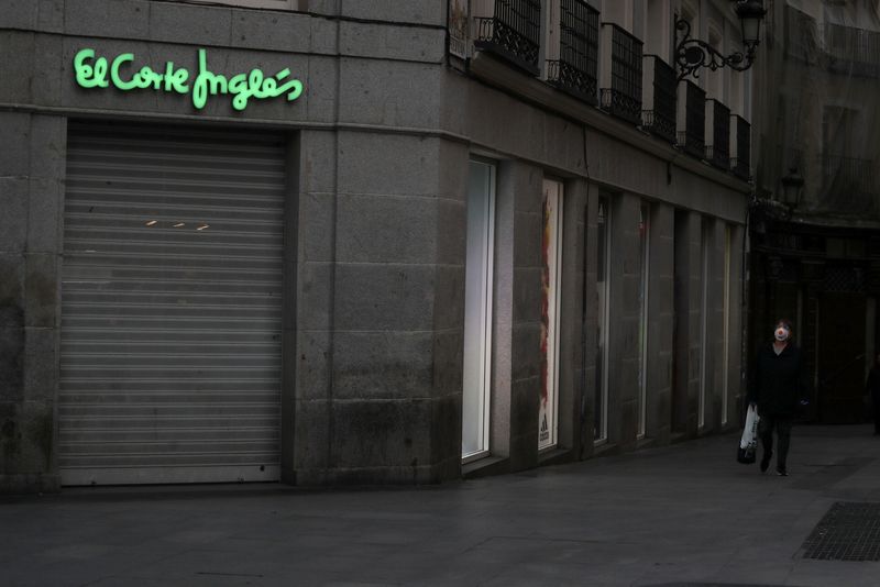 FILE PHOTO: A woman wearing a protective mask walks past a closed down El Corte Ingles department store in Madrid