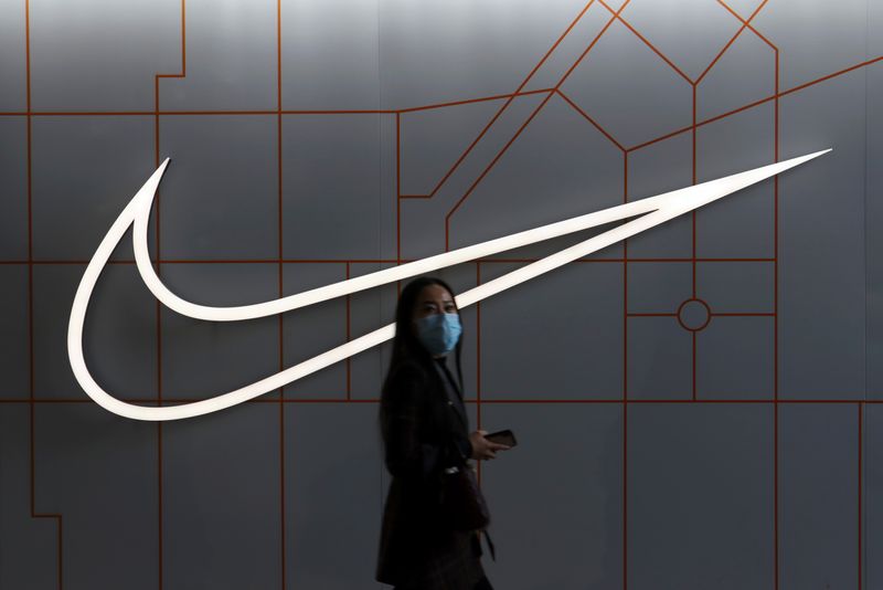 FILE PHOTO: Woman walks past a Nike Inc store at a shopping complex in Beijing