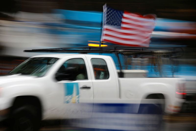 A PG&E truck carrying an American Flag drives past PG&E repair trucks in Paradise