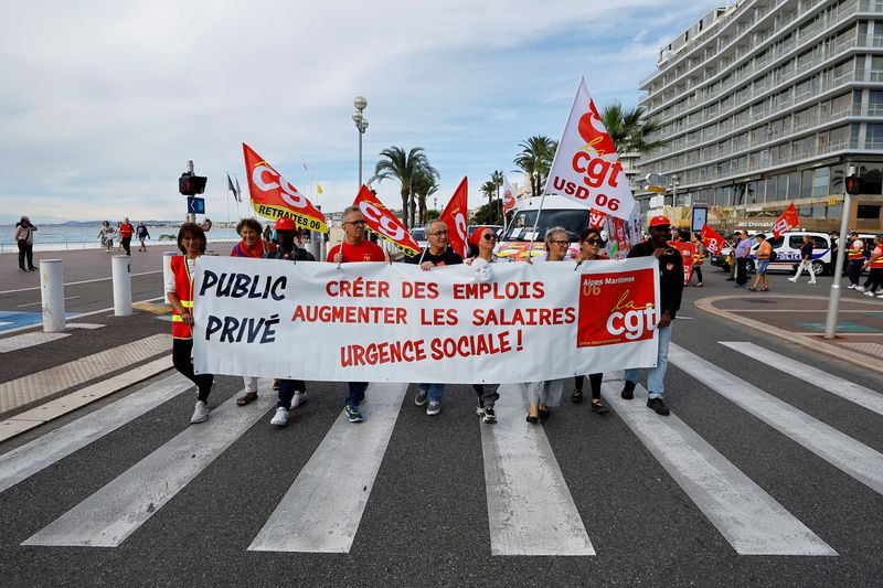 Des manifestant portent des drapeaux et une banderole de la CGT sur la Promenade des Anglais à Nice