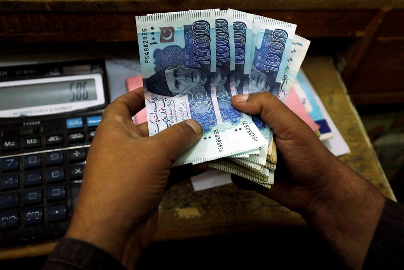 FILE PHOTO: A trader counts Pakistani rupee notes at a currency exchange booth in Peshawar