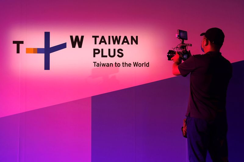 A staff member takes a video of the TaiwanPlus logo, in Taipei