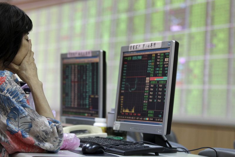 A woman monitors stock market prices inside a brokerage in New Taipei city
