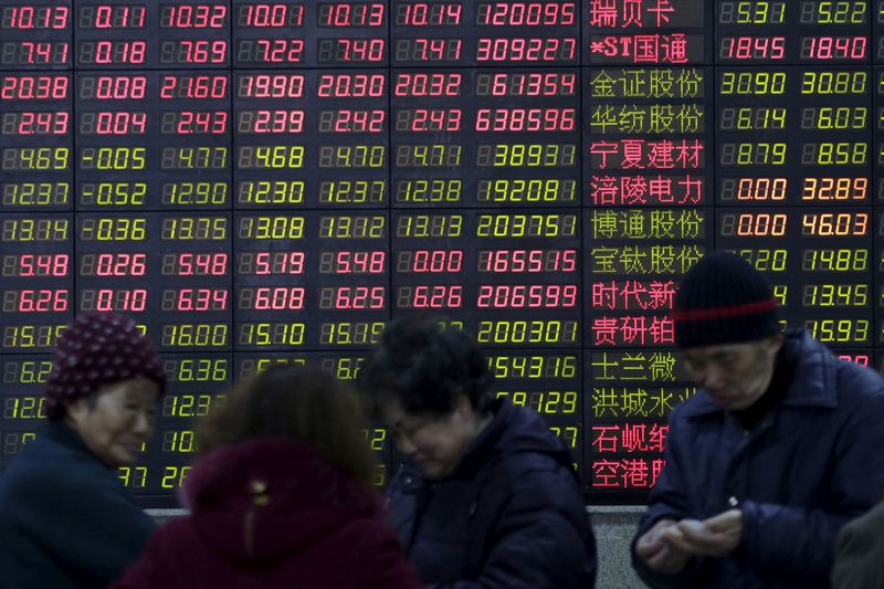 FILE PHOTO: Investors stand in front of an electronic board showing stock information on the first trading day after the week-long Lunar New Year holiday at a brokerage house in Shanghai