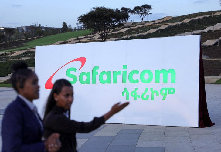 Safaricom Ethiopia employees walk past a billboard during the Safaricom ceremony to officially launch its operations in Ethiopia, in Addis Ababa
