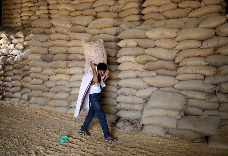 FILE PHOTO: A worker carries a sack of wheat for sifting at a grain mill on the outskirts of Ahmedabad