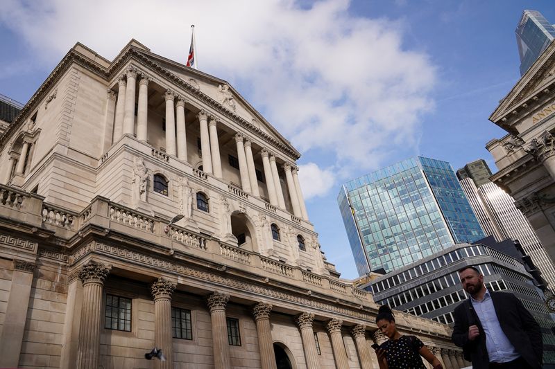 People walk past Bank of England in the City of London financial district in London