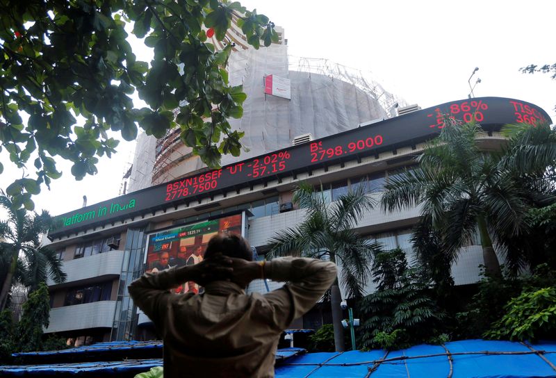 A man watches a large screen displaying India's benchmark share index on the facade of BSE building in Mumbai