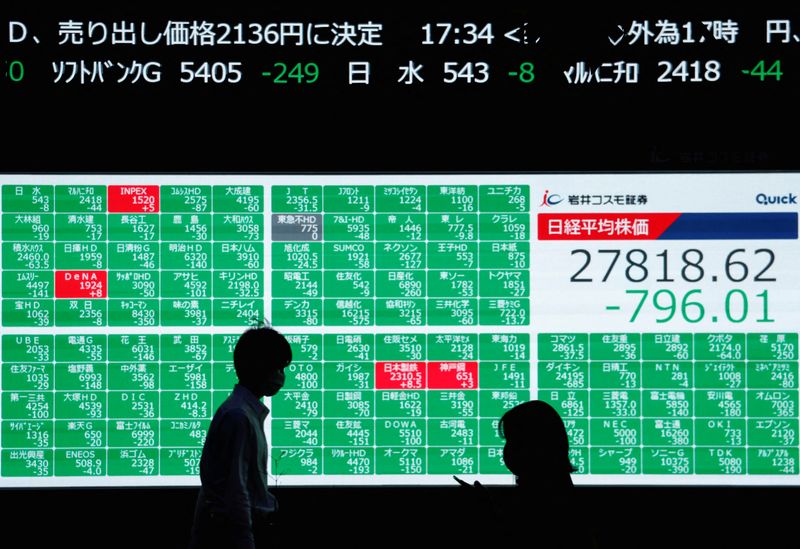 People walk past an electric board showing Japan's Nikkei share average in Tokyo