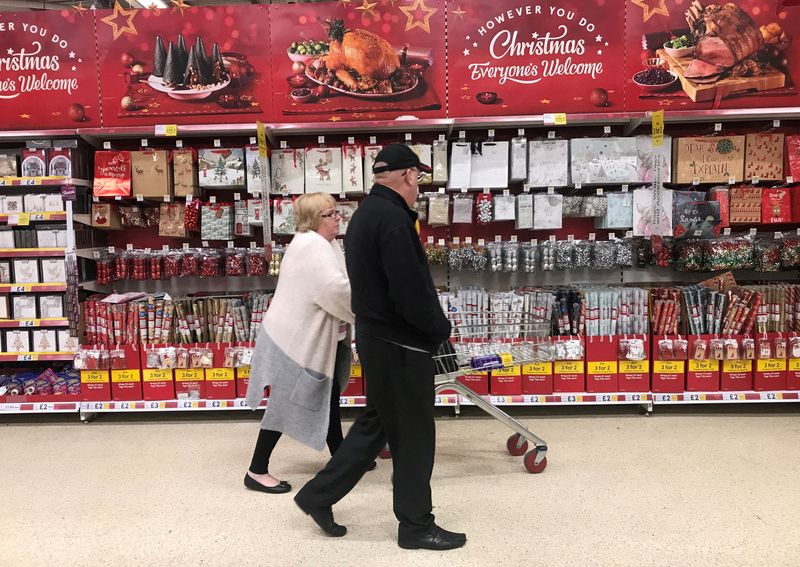 FILE PHOTO: A woman pushes a shopping trolley past Christmas decorations for sale in a Tesco store in Manchester