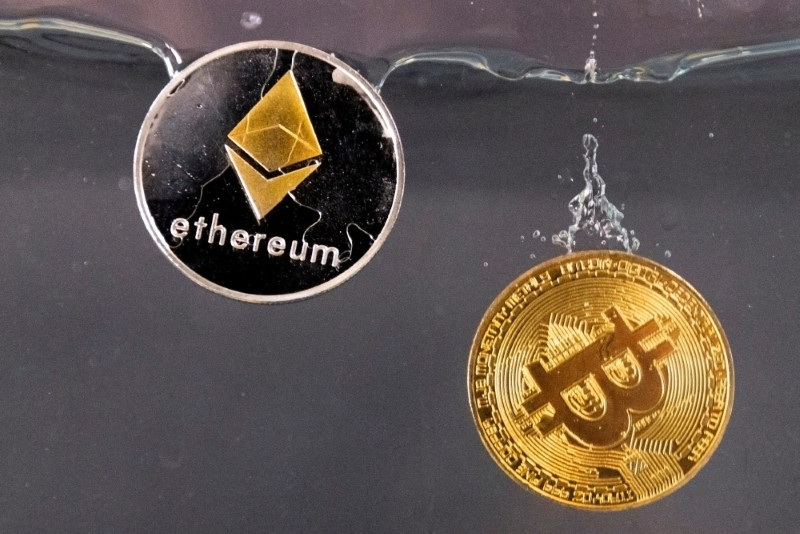 FILE PHOTO: Bitcoin and ether souvenir tokens plunge into water