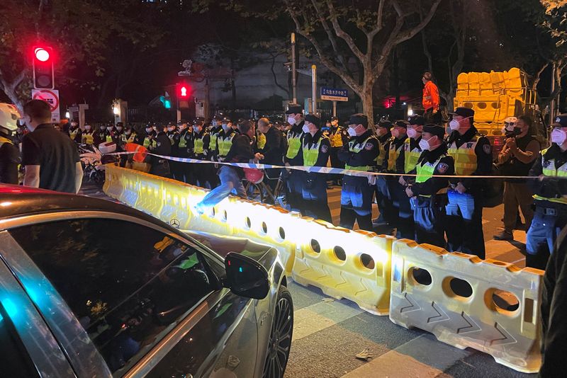 Des policiers derrière des barricades sur le site où une manifestation contre les restrictions liées au COVID-19 a eu lieu la nuit précédente, à Shanghai, en Chine