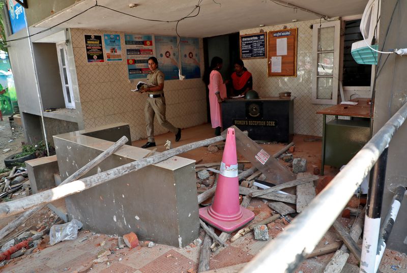 A police officer walks past rubble after a clash with protesters at a police station near the proposed Vizhinjam Port