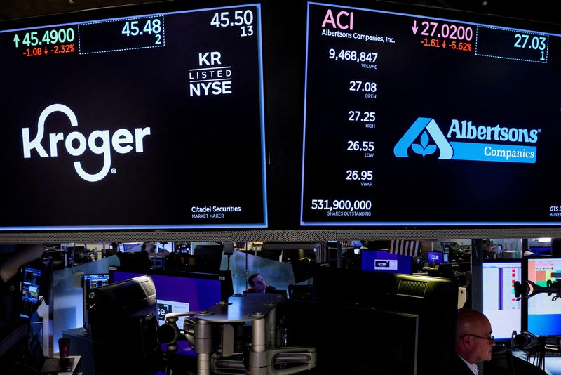 FILE PHOTO: Traders work as screens display the trading information for Kroger and Albertsons on the floor of the NYSE in New York