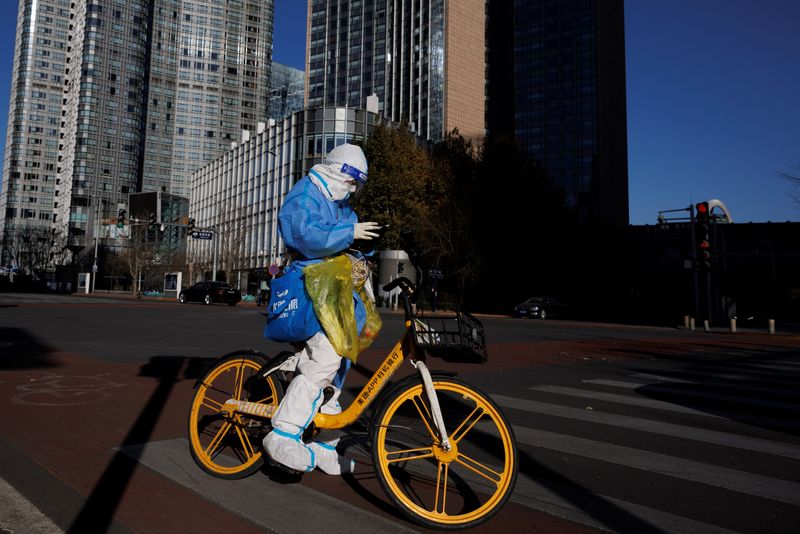 A health worker in a protective suit waits at a traffic light in a street in the central business district (CBD) that is largely deserted because of work-from-home orders as coronavirus disease (COVID-19) outbreaks continue in Beijing