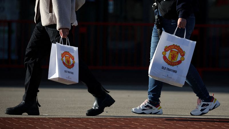 FILE PHOTO: People with Manchester United bags outside Old Trafford stadium