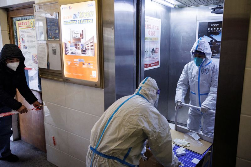 Pandemic prevention workers in protective suits enter an apartment building that went into lockdown as coronavirus disease (COVID-19) outbreaks continue in Beijing
