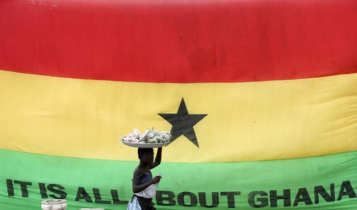 FILE PHOTO: Girl walks past a flag of Ghana outside the former slave trading Cape Coast Castle