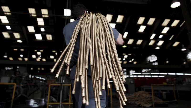 An employee carries copper hoses at the SPTF metallurgical company in Sao Paulo