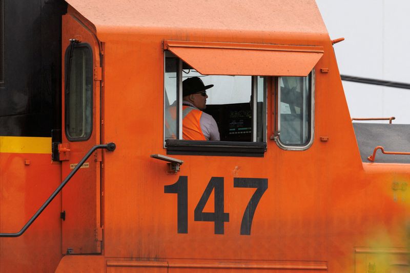 FILE PHOTO: Railway workers load railcars onto train in California