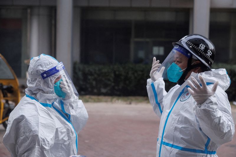 FOTO DE ARCHIVO: Trabajadores de prevención de la pandemia con trajes de protección se preparan para entrar en un edificio de apartamentos que entró en confinamiento mientras continúan los brotes de COVID-19 en Pekín