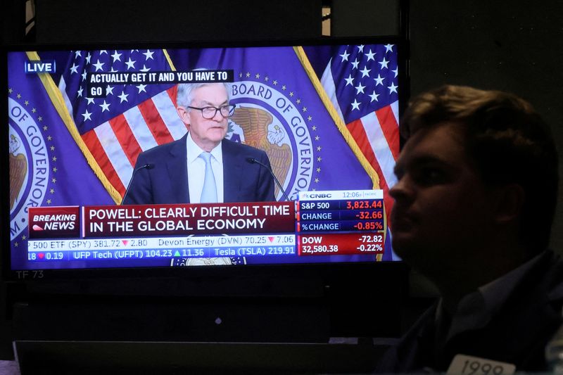 FILE PHOTO: A screen displays Federal Reserve Chair Powell speaking as a trader works on the floor of the NYSE in New York