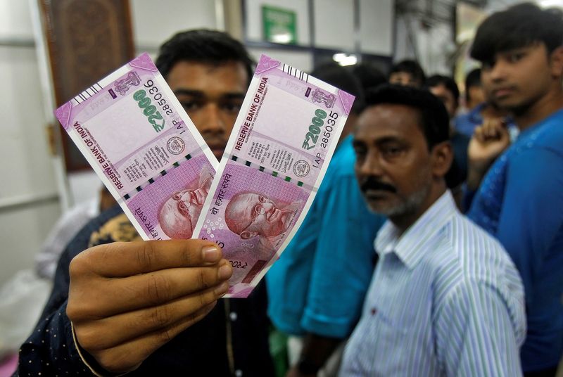 A man displays the new 2000 Indian rupee banknotes after withdrawing them from State Bank of India in Agartala