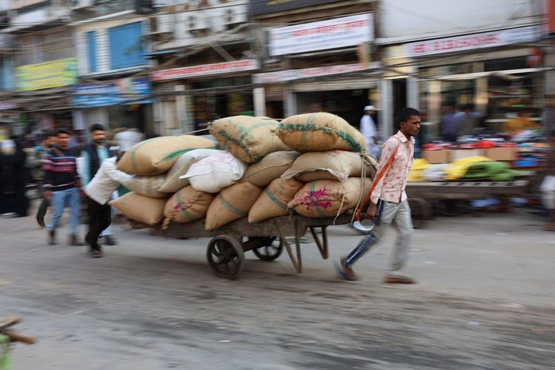 Workers transport sacks that are loaded on a cart at a wholesale market in the old quarters of Delhi
