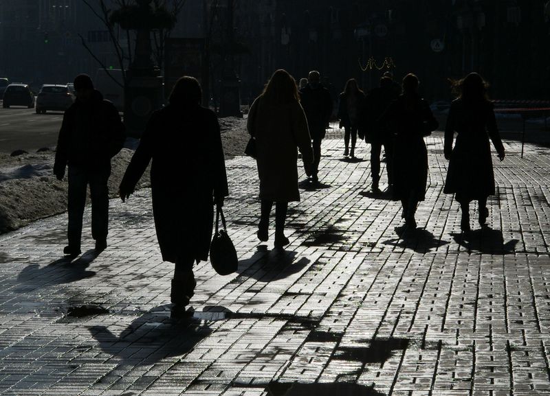 FILE PHOTO: Pedestrians are silhouetted as they walk on a sunny day in central Kyiv
