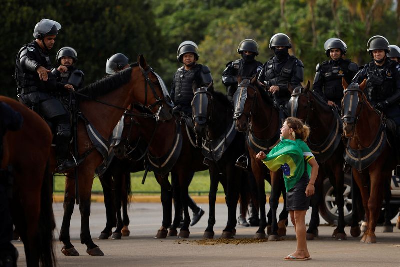 Un manifestant et des membres des forces de sécurité pendant le démantèlement d'un camp de partisans de l'ancien président brésilien Jair Bolsonaro devant le siège de l'armée, à Brasilia