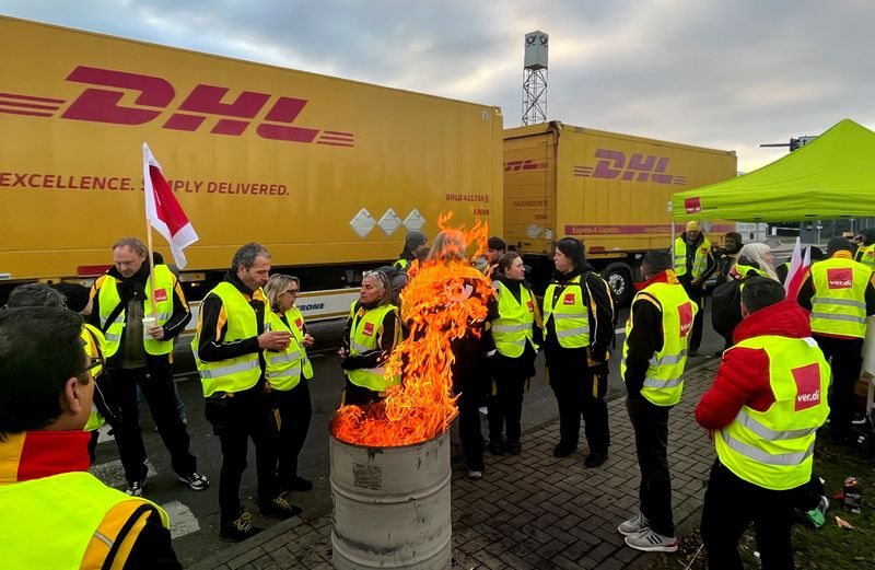 Postarbeiter neben einer Feuertonne während eines bundesweiten Warnstreiks bei der Deutschen Post in Köln, Deutschland, 20. Januar 2023