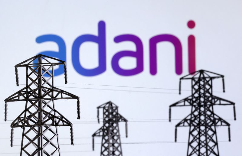 Illustration shows Electric power transmission pylon miniatures and Adani Green Energy logo