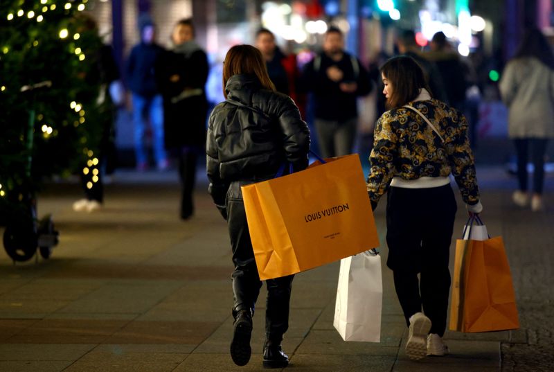 Women with shopping bags branded with Louis Vuitton walk outside the department store 
