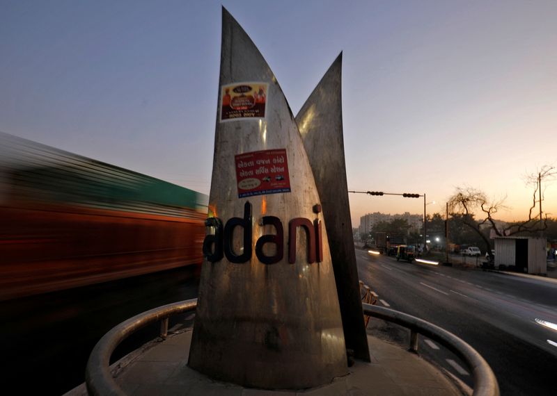 FILE PHOTO: Traffic moves past the logo of the Adani Group installed at a roundabout on the ring road in Ahmedabad